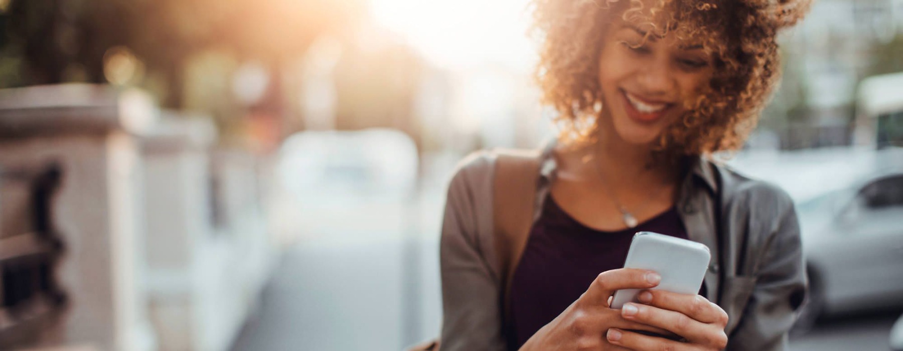woman texts on her phone as she walks through the city